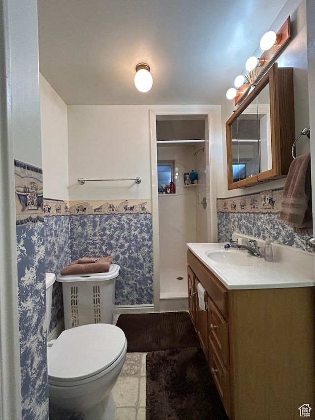 bathroom featuring vanity, tile walls, toilet, a wainscoted wall, and a stall shower