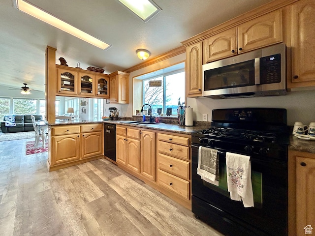 kitchen featuring black appliances, light wood-style floors, a sink, and a healthy amount of sunlight