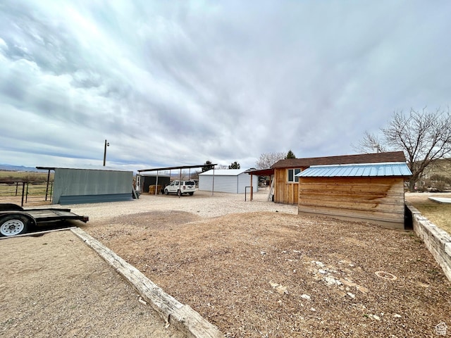 view of yard featuring driveway, a pole building, and an outdoor structure