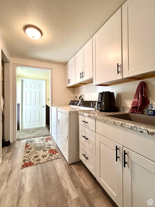 laundry room featuring independent washer and dryer, wood finished floors, cabinet space, and a textured ceiling