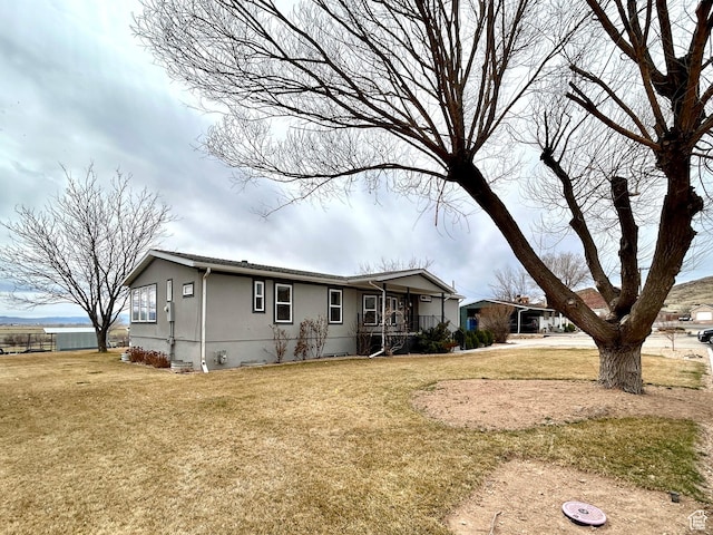 view of front of house featuring stucco siding, covered porch, and a front lawn