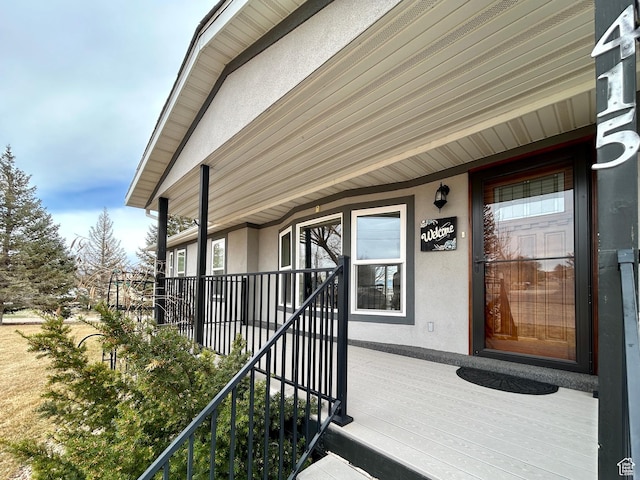 doorway to property with stucco siding and covered porch