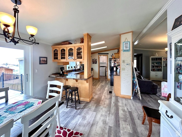 kitchen featuring a notable chandelier, crown molding, freestanding refrigerator, light wood finished floors, and glass insert cabinets