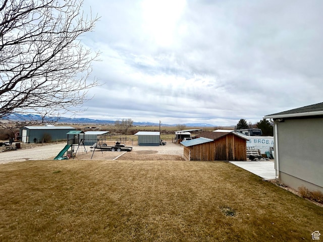 view of yard featuring a shed, an outdoor structure, and a playground