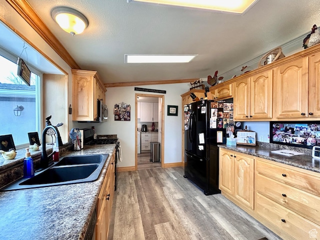 kitchen with stainless steel microwave, black fridge, range, a sink, and light brown cabinets