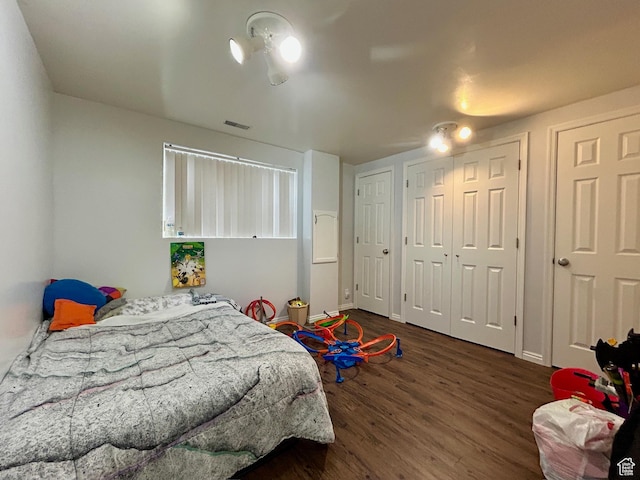 bedroom with baseboards, visible vents, and wood finished floors