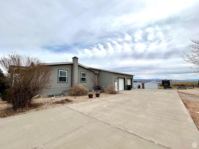 view of home's exterior featuring stucco siding, driveway, a chimney, and an attached garage