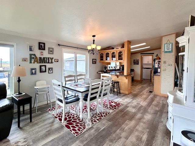 dining room featuring a notable chandelier, ornamental molding, lofted ceiling, and light wood-type flooring