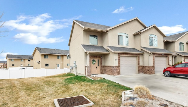 view of property with stucco siding, fence, an attached garage, driveway, and a front yard