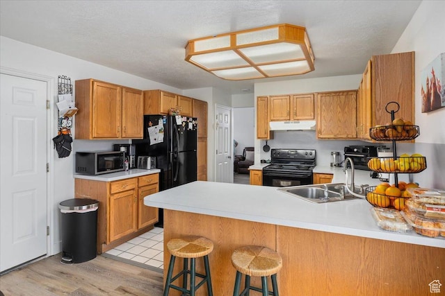 495 W 1330 N, Logan, UT 84341 - kitchen featuring black appliances, a sink, a peninsula, under cabinet range hood, and light countertops
