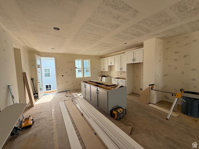 kitchen with a center island, independent washer and dryer, wallpapered walls, and white cabinets