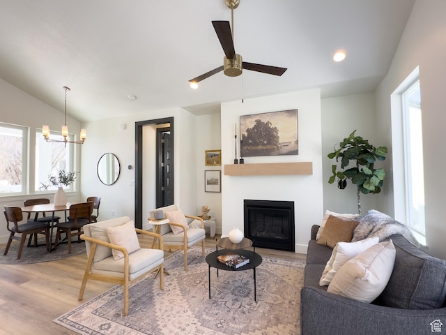 living area featuring plenty of natural light, ceiling fan with notable chandelier, lofted ceiling, and light wood finished floors