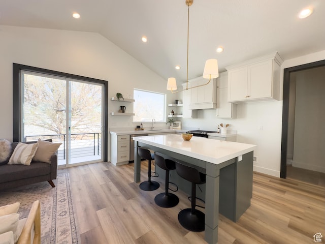 kitchen featuring light countertops, open shelves, light wood-type flooring, a kitchen island, and a sink