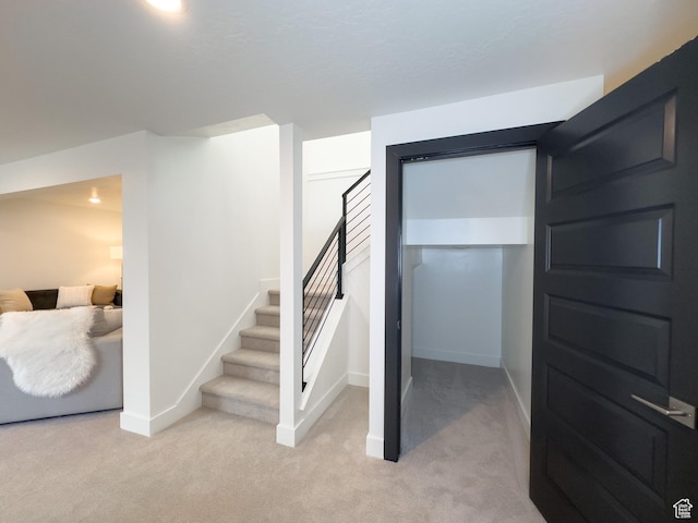basement with baseboards, light colored carpet, and stairs