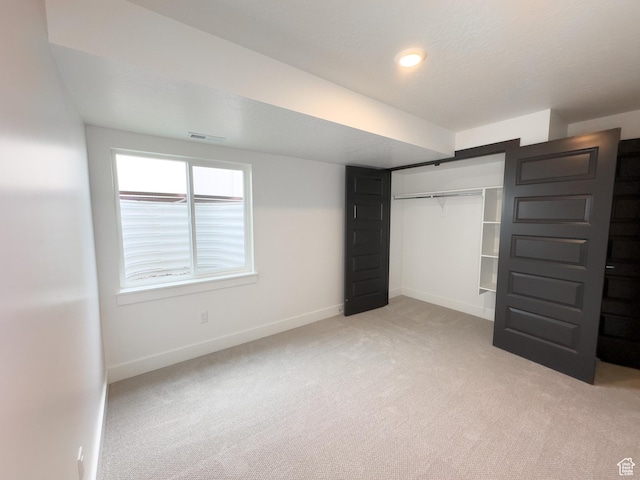 unfurnished bedroom with a closet, light carpet, baseboards, and visible vents