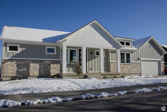 view of front of house featuring stone siding, an attached garage, and board and batten siding