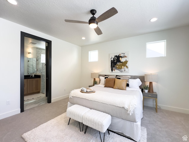 bedroom featuring baseboards, light colored carpet, and a textured ceiling