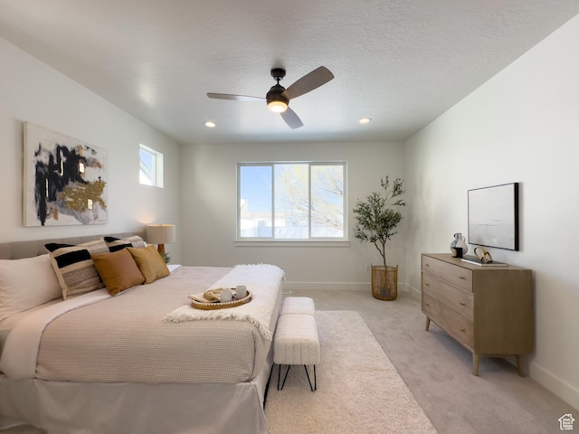 bedroom with baseboards, a textured ceiling, ceiling fan, and light carpet