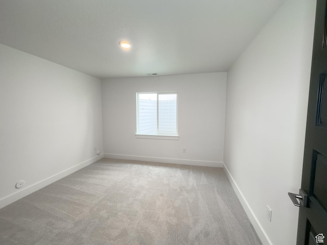 spare room featuring baseboards, visible vents, and light colored carpet