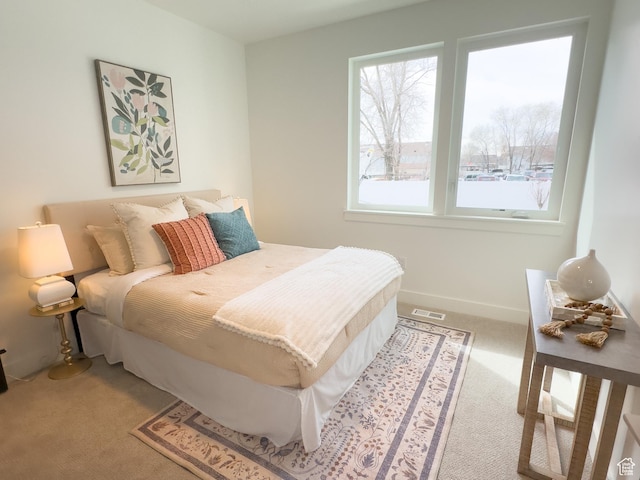 bedroom with baseboards, light colored carpet, and visible vents