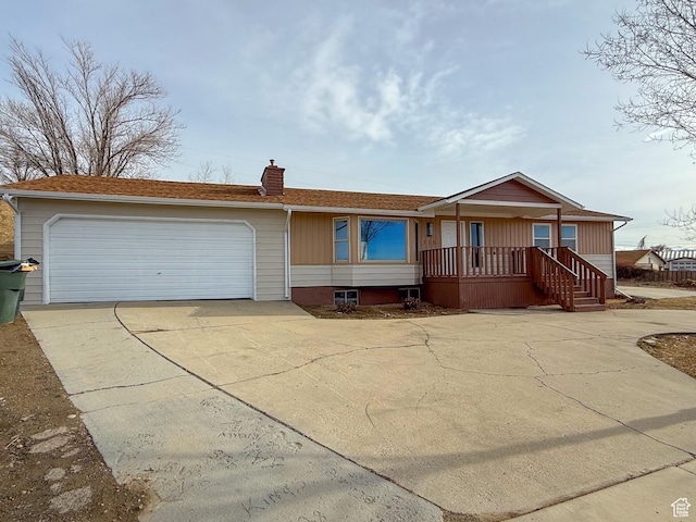 view of front facade with driveway, a porch, a chimney, and a garage