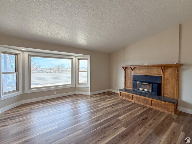 510 W Highway Dr, Wellington, UT 84542 - unfurnished living room featuring baseboards, lofted ceiling, wood finished floors, and a glass covered fireplace