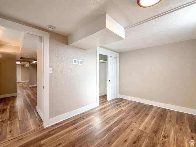 510 W Highway Dr, Wellington, UT 84542 - unfurnished bedroom with wood finished floors, a textured ceiling, baseboards, visible vents, and a textured wall