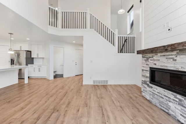 951 W Cushing Rd, Bluffdale, UT 84065 - unfurnished living room featuring stairs, a stone fireplace, light wood-style flooring, baseboards, and visible vents