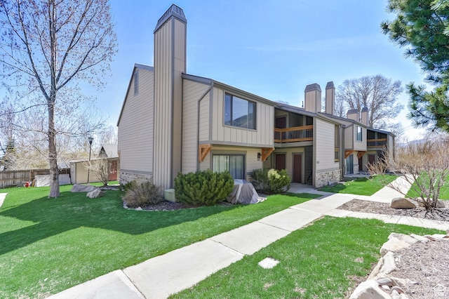 1637 Village Round Dr Unit 8, Park City, UT 84098 - rear view of house with a chimney, fence, stone siding, a balcony, and a lawn