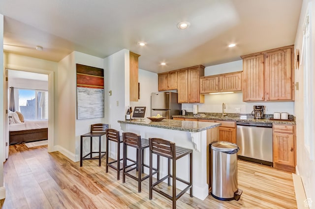 1637 Village Round Dr Unit 8, Park City, UT 84098 - kitchen featuring a peninsula, stainless steel appliances, dark stone countertops, light wood-type flooring, and a breakfast bar area