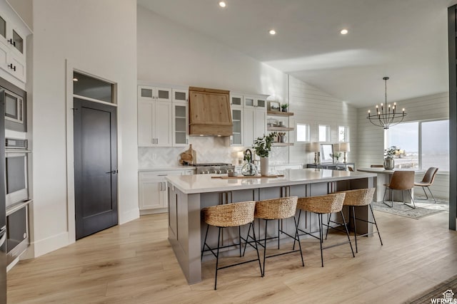 kitchen with light wood-style flooring, oven, a kitchen island, white cabinetry, and a sink