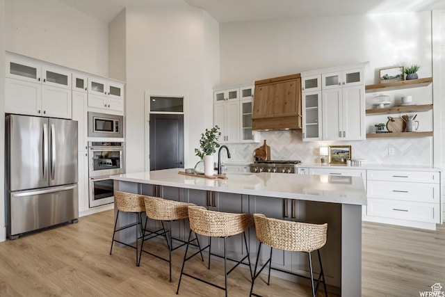 kitchen featuring light countertops, a sink, tasteful backsplash, stainless steel appliances, and light wood-style floors