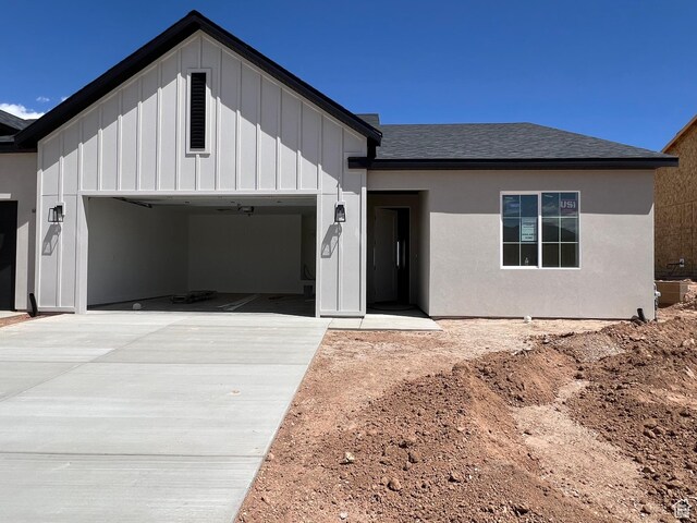 330 W Rosie Loop Unit 45E, Cedar City, UT 84720 - view of front facade with a garage, driveway, board and batten siding, roof with shingles, and central AC unit