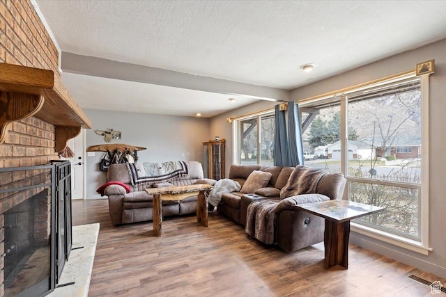 613 N 100 E, Brigham City, UT 84302 - living area featuring a textured ceiling, visible vents, light wood-type flooring, and a brick fireplace