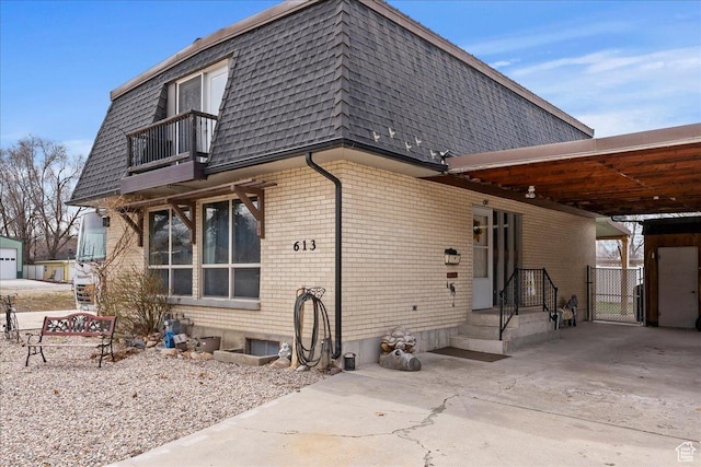 613 N 100 E, Brigham City, UT 84302 - rear view of house featuring driveway, an attached carport, mansard roof, brick siding, and a balcony