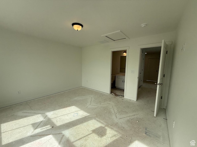 unfurnished bedroom with connected bathroom, attic access, and baseboards