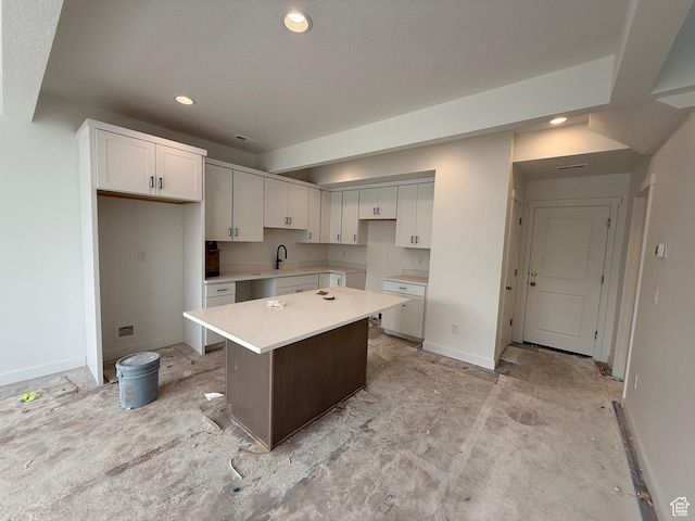 kitchen with white cabinetry, recessed lighting, a center island, baseboards, and a sink