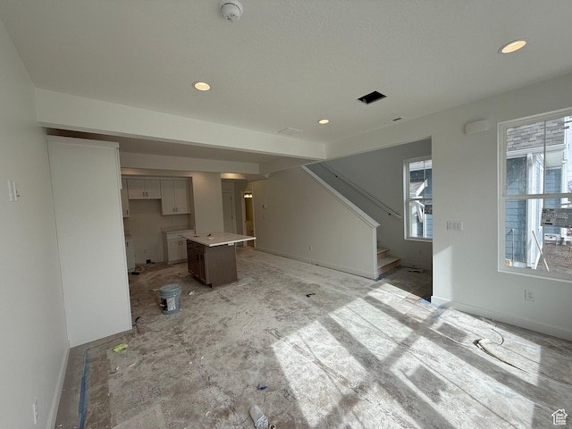unfurnished living room with baseboards, recessed lighting, and stairway