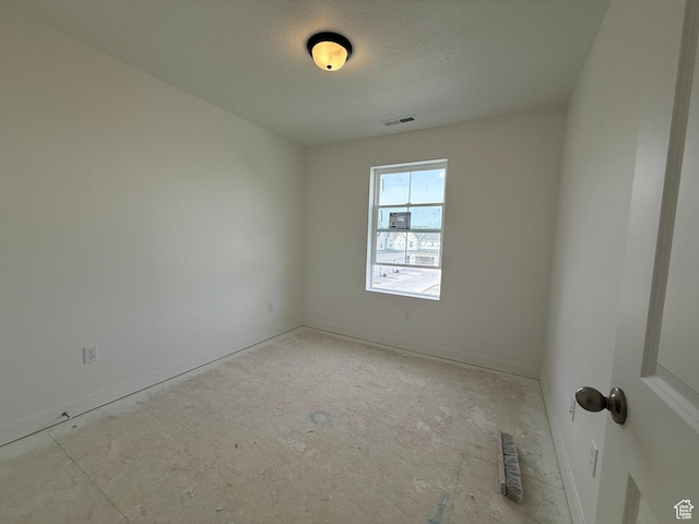 empty room featuring baseboards, visible vents, and a textured ceiling