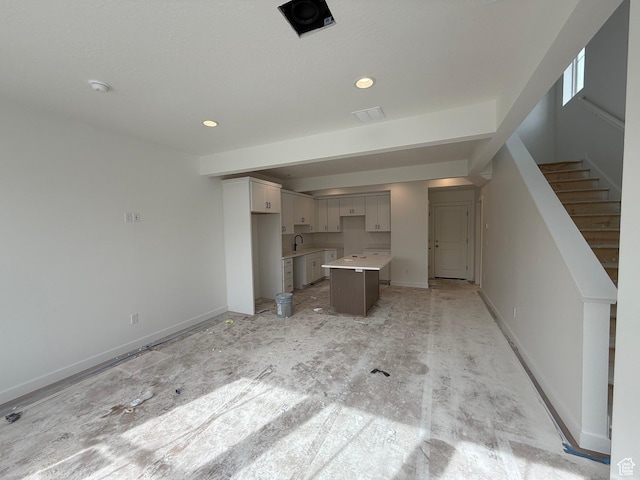 unfurnished living room with baseboards, recessed lighting, a sink, and stairway