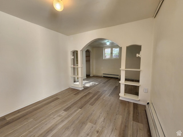383 S 100 W, Price, UT 84501 - spare room with baseboard heating, wood finished floors, arched walkways, and a baseboard radiator