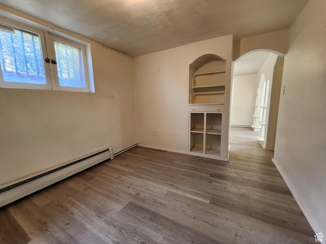 383 S 100 W, Price, UT 84501 - unfurnished room featuring baseboard heating, arched walkways, wood finished floors, and baseboards