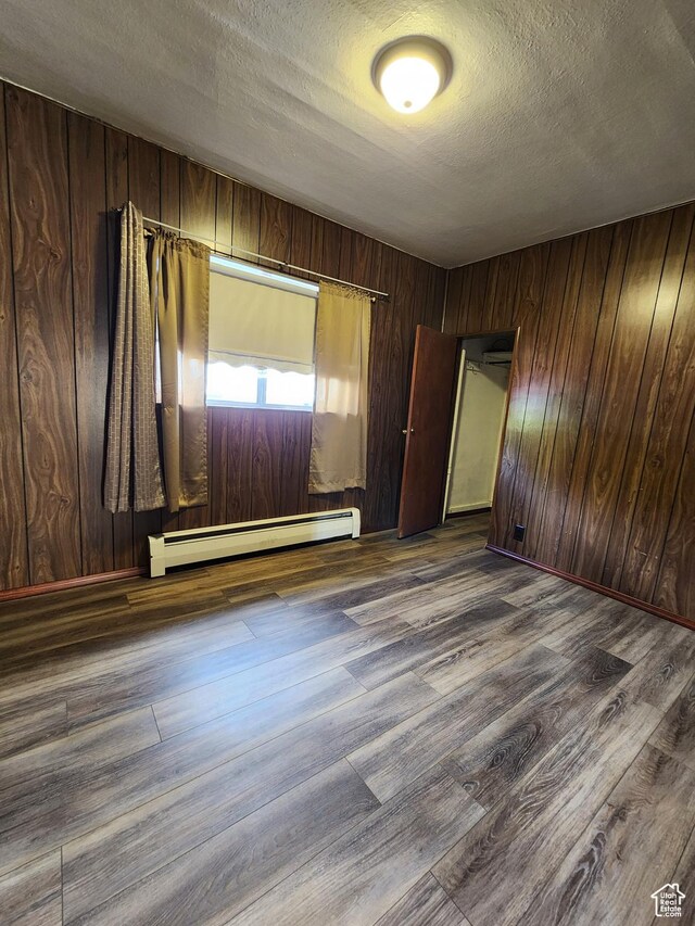 383 S 100 W, Price, UT 84501 - spare room featuring a baseboard radiator, dark wood-type flooring, a textured ceiling, and wood walls