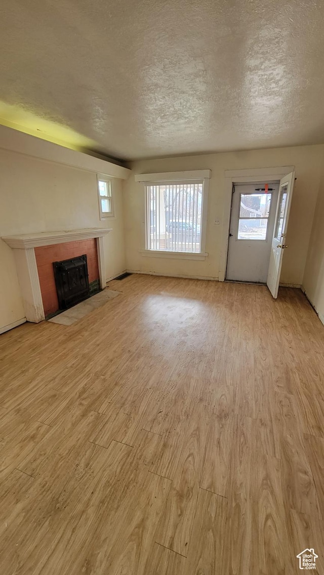 390 S 400 W, Logan, UT 84321 - unfurnished living room featuring a textured ceiling, a wealth of natural light, a tile fireplace, and light wood finished floors
