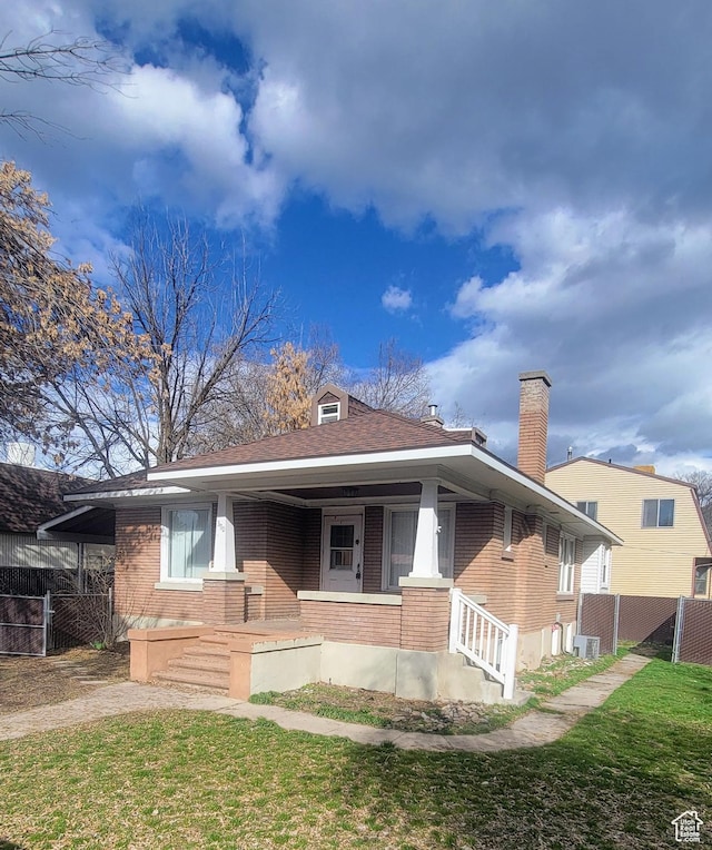 390 S 400 W, Logan, UT 84321 - view of front of house with brick siding, fence, a shingled roof, and a front yard