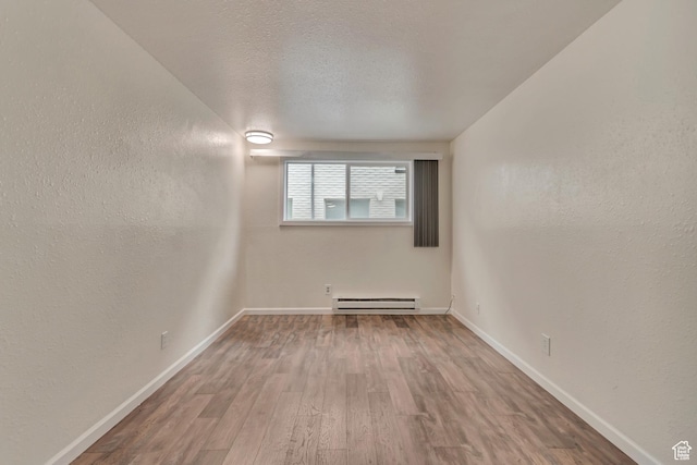 742 S 400 E Unit H102, Salt Lake City, UT 84111 - empty room with a textured wall, baseboards, a textured ceiling, a baseboard radiator, and wood finished floors