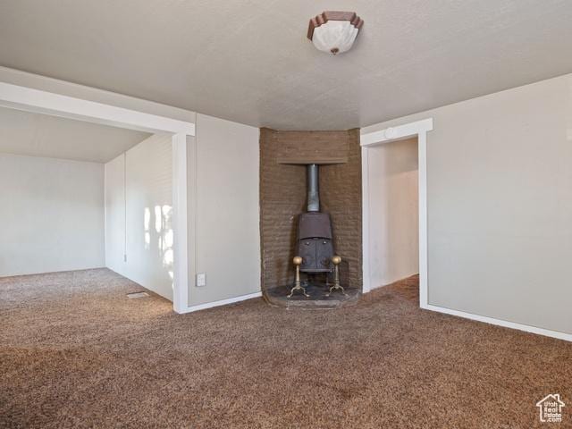 unfurnished living room featuring a wood stove and carpet