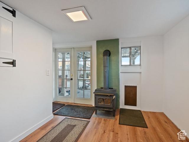 doorway with light wood finished floors, baseboards, a wood stove, and french doors