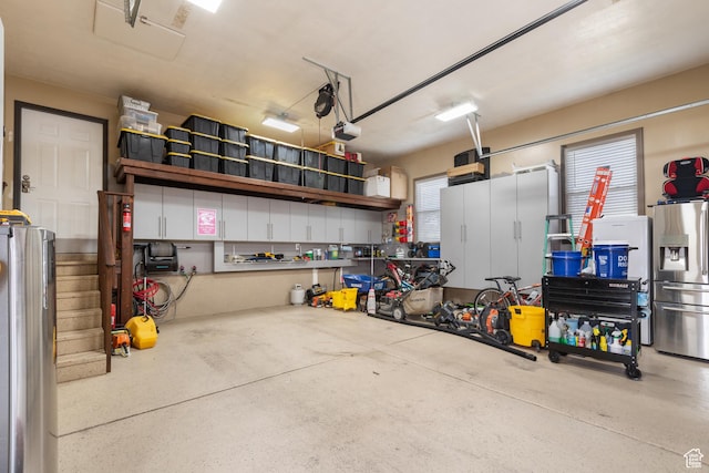 12381 S 3600 W, Riverton, UT 84065 - garage featuring a garage door opener, stainless steel fridge, and freestanding refrigerator