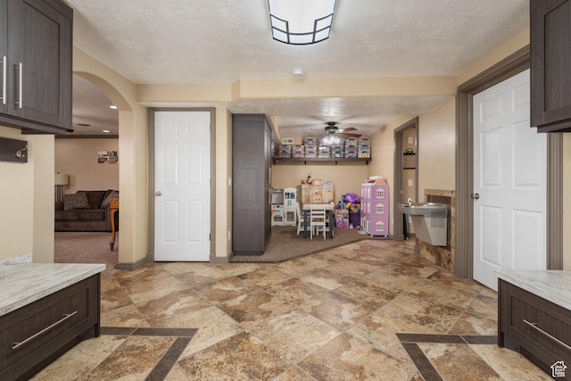 12381 S 3600 W, Riverton, UT 84065 - kitchen with a textured ceiling, light countertops, dark brown cabinets, a ceiling fan, and arched walkways